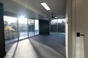 Empty room featuring a wall of windows and ceiling fan