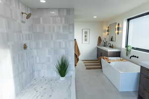 Bathroom featuring shower with separate bathtub and vanity