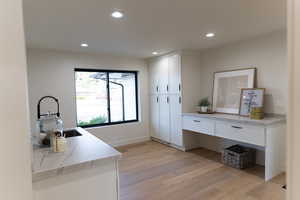 Interior space with white cabinets, kitchen peninsula, sink, and light hardwood / wood-style flooring