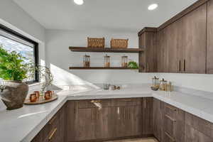 Kitchen featuring dark brown cabinets and light stone countertops