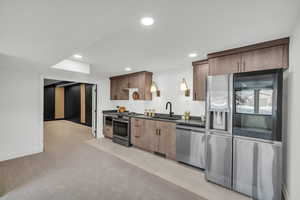 Kitchen featuring sink, light carpet, and stainless steel appliances