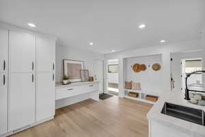 Interior space featuring light wood-type flooring, white cabinetry, and light stone countertops