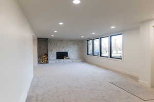 Unfurnished living room with a fireplace and light carpet