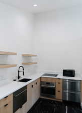 Kitchen with light brown cabinetry, sink, and black appliances