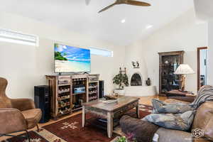 Living room featuring hardwood / wood-style floors, a large fireplace, vaulted ceiling, and ceiling fan