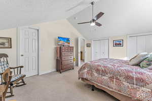 Bedroom featuring multiple closets, ceiling fan, light carpet, and a textured ceiling