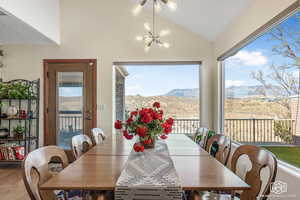 Dining space with hardwood / wood-style flooring, a mountain view, vaulted ceiling, and a chandelier