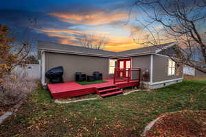 Back house at dusk with a yard and a deck