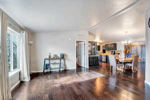 Dining space with a chandelier, dark hardwood / wood-style flooring, a healthy amount of sunlight, and vaulted ceiling