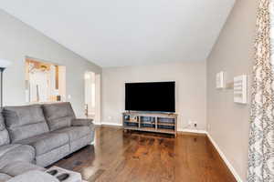 Living room with dark wood-type flooring and vaulted ceiling