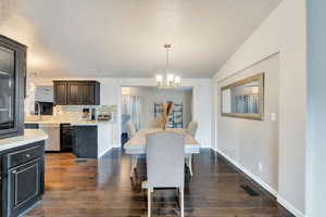 Dining room with a textured ceiling, dark hardwood / wood-style floors, sink, and an inviting chandelier