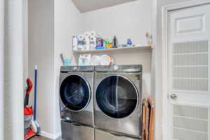 Washroom featuring washing machine and dryer and a textured ceiling