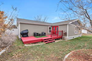 Rear view of house with french doors, a deck, and a lawn