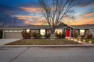 Ranch-style home featuring a garage and a lawn