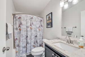 Full bathroom featuring shower / bath combo, toilet, a textured ceiling, and vanity