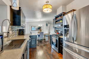 Kitchen with pendant lighting, stainless steel appliances, tasteful backsplash, and a notable chandelier