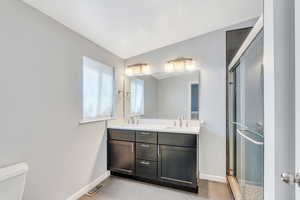 Bathroom featuring vanity, tile patterned floors, toilet, a textured ceiling, and an enclosed shower