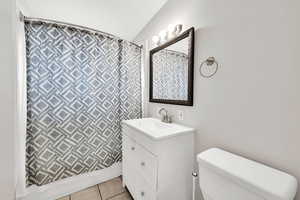 Bathroom with toilet, vanity, and tile floors