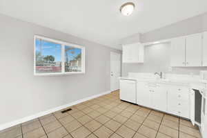 Kitchen featuring white cabinets, white appliances, light tile patterned flooring, and sink