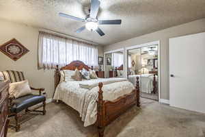 Bedroom featuring carpet flooring, a textured ceiling, ceiling fan, and multiple closets