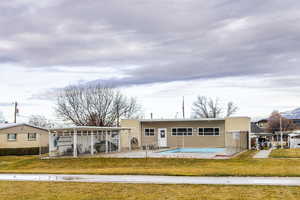 Rear view of house featuring a lawn, a patio, and an empty pool