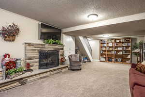 Living room featuring carpet flooring, a fireplace, and a textured ceiling