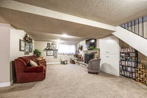 Living room with a fireplace, carpet floors, and a textured ceiling