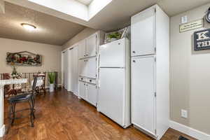 Kitchen with white cabinets, wood-type flooring, a textured ceiling, and white refrigerator