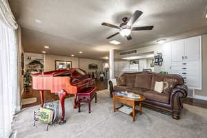 Living room with ceiling fan and a textured ceiling