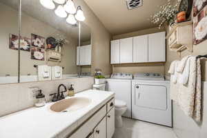 Bathroom with tasteful backsplash, vanity, washer and dryer, and toilet