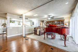 Miscellaneous room featuring hardwood / wood-style flooring, ceiling fan, and a textured ceiling