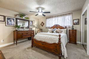 Bedroom with light carpet, a textured ceiling, a closet, and ceiling fan