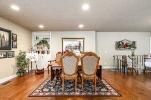 Dining space with built in shelves, a textured ceiling, and hardwood / wood-style floors