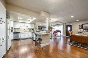 Kitchen featuring kitchen peninsula, appliances with stainless steel finishes, a kitchen bar, sink, and white cabinets