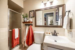 Bathroom featuring vanity, toilet, and a shower with door