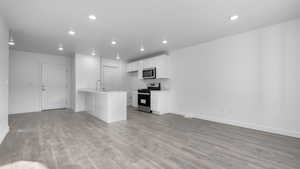 Kitchen with kitchen peninsula, white cabinetry, stainless steel appliances, and light wood-type flooring