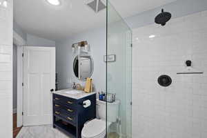 Bathroom with a tile shower, vanity, and toilet