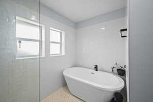 Bathroom featuring tile patterned flooring, tile walls, and a bathing tub