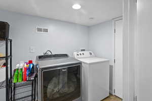 Laundry area with light hardwood / wood-style flooring and washer and dryer