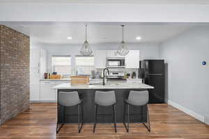 Kitchen with white cabinets, a center island with sink, and stainless steel appliances