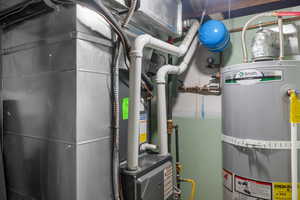 Utility room featuring furnace and strapped water heater