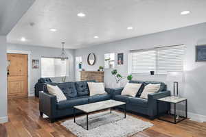 Living room featuring a stone fireplace, and dark wood-type flooring