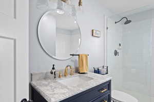 Bathroom featuring toilet, vanity, and tiled shower