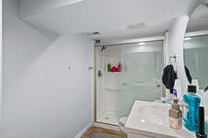 Bathroom featuring vanity, a shower with shower door, and toilet