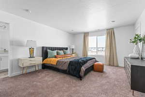 Bedroom featuring ensuite bath, light colored carpet, and a textured ceiling