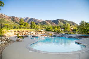 Community pool featuring fence, a patio, and a mountain view