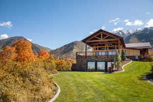 Back of property with a mountain view, a yard, and stone siding