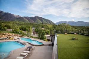 Community pool with fence, a patio, and a mountain view