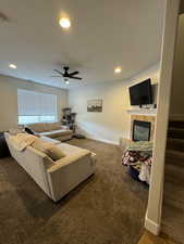 Living room with carpet, ceiling fan, and a tile fireplace