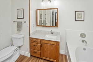 Bathroom with a bathtub, vanity, hardwood / wood-style floors, and toilet